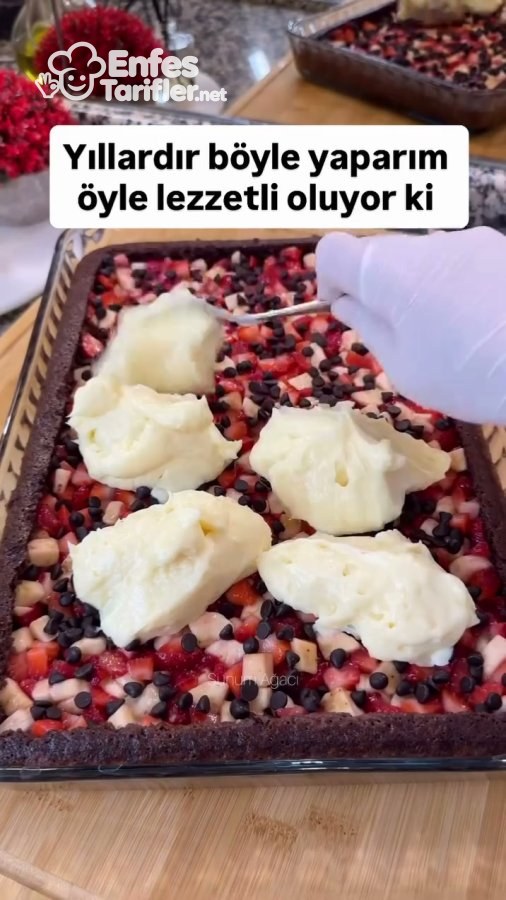 Muz, çilek ve damla çikolatalı kek tabanının üzerine kremanın eklenmesi