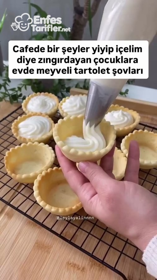 Pişmiş tart kabuğunun içine sıkma torbasıyla beyaz krema doldurulması