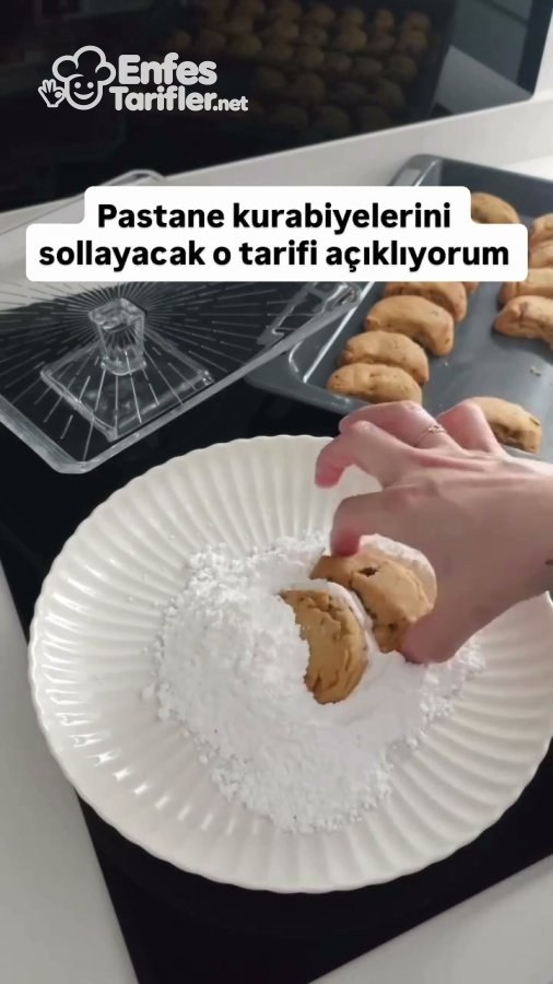 Pişmiş ay şeklindeki cevizli kurabiyenin pudra şekerine bulanması
