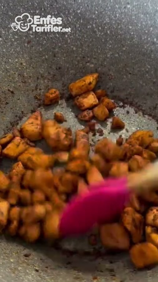 Tavada spatulayla çevrilen baharatlı küçük tavuk parçaları