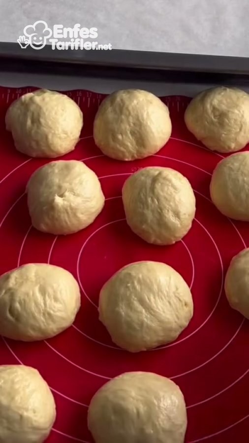 Tezgâhtaki hamur bezelerinden birinin kaşarlı iç harç eklemek için elde açılması