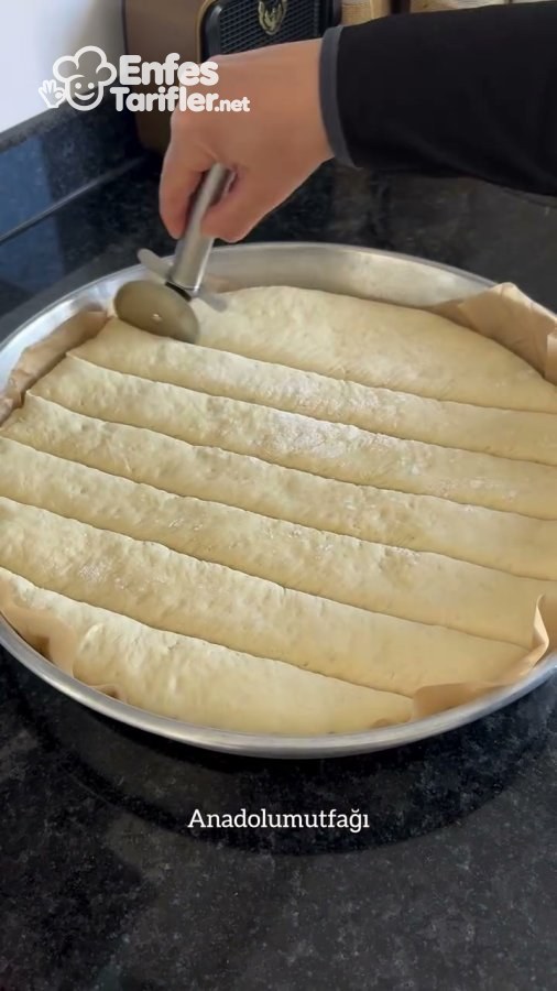 Tepsideki mayalı hamurun pizza kesiciyle paralel şeritler halinde kesilmesi