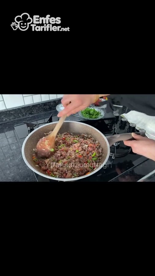 Tavada kıyma ve doğranmış biberlerin tahta kaşıkla kavrulması