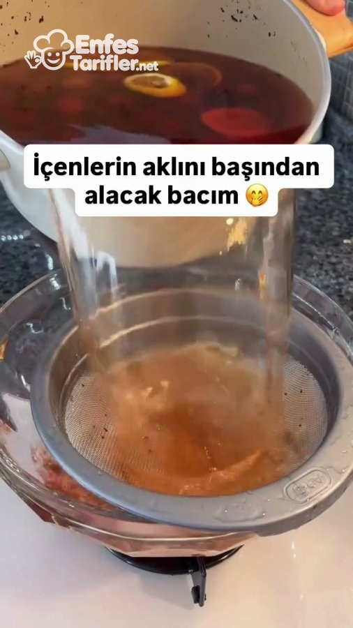 Demlenen kirazlı çayın ince süzgeçten geçirilmesi