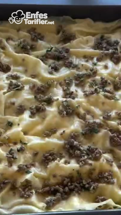 Tepsideki kıvrımlı su böreği yufkasının üzerine dağıtılmış kıymalı harç