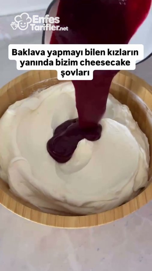 Beyaz cheesecake kremasının üzerine koyu renkli orman meyvesi sosunun eklenmesi