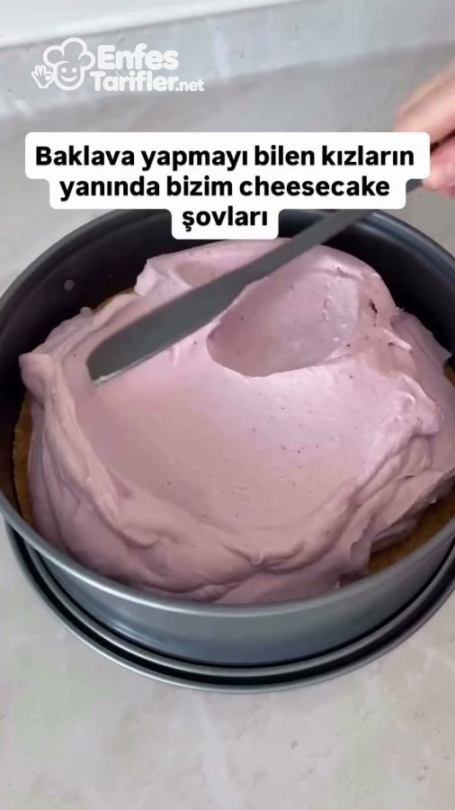 Kelepçeli kalıptaki pembe meyveli cheesecake dolgusunun spatulayla düzeltilmesi