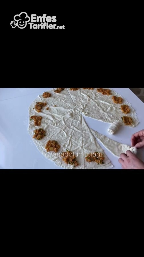 Patatesli harç konmuş üçgen yufkanın geniş kenarından rulo sarılması