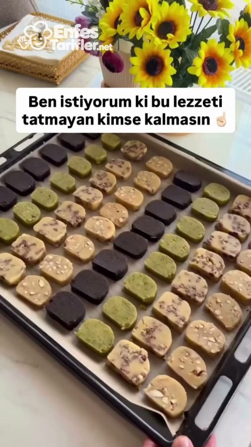 Dört çeşit dilimlenmiş kurabiyenin pişirme kâğıdı serili fırın tepsisine dizilmiş hali
