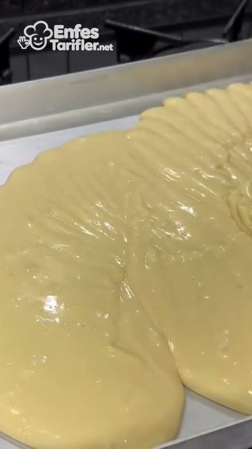 Kek hamurunun pişirme kâğıdı serilmiş dikdörtgen tepsiye dökülmesi.